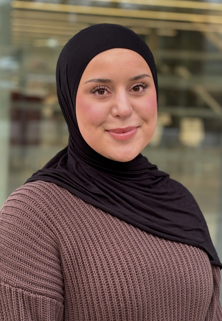 Eda Kaya lächelt in die Kamera. Sie trägt einen dunklen Hidschab und ein braunes Oberteil.